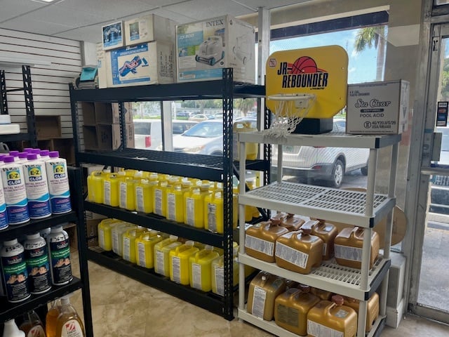 Interior of automotive retail store with shelves displaying yellow and white product boxes, cleaning supplies, and vehicle signage on walls