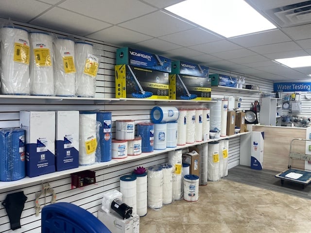 Store shelves displaying water testing kits, filters, and related products in blue and white packaging