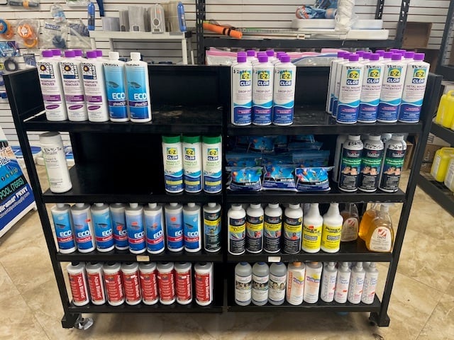 A mobile display stand stocked with various spray paint cans and aerosol products organized on multiple black shelves