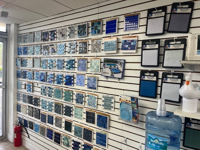 Retail wall display with blue tile samples organized on slatwall, storage bins, and containers
